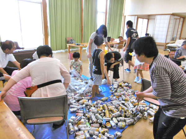 出雲サンホームのスタッフと利用者の方と地域の方々との空き缶つぶしの様子